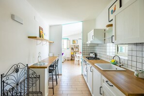 A modern kitchen with wooden countertops, a sink, and a dining area with chairs and a table. - Viewsuvio Family Terrace (Naples)