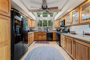 A kitchen with wooden cabinets, a black refrigerator, a microwave, and a ceiling fan. - Downtown Breck Retreat| Deck + Trails + Hot Tub (Breckenridge)