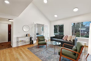 A spacious living room with a large window, a sofa, a coffee table, and a chair. - The Dale Home (Seattle)