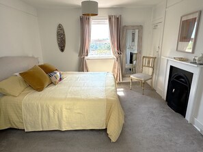 A bedroom with a bed, a chair, a fireplace, and a window with curtains. - Superb Hastings Old Town Duplex with parking and sea views (Hastings)
