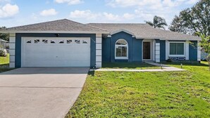 A single-story house with a garage, a front door, and a small porch. - Cozy Carribean/Mediterranean Home in Kissimmee, FL (Kissimmee)