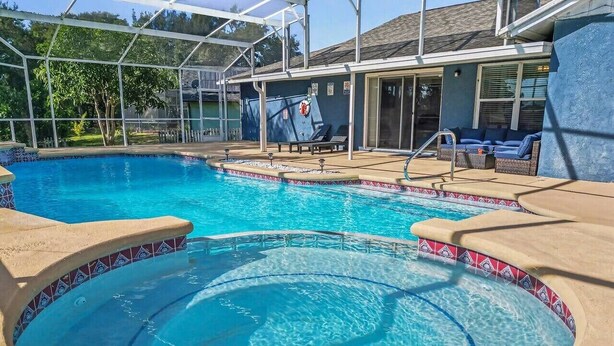 A swimming pool with a sunshade, lounge chairs, and a covered seating area. - Cozy Carribean/Mediterranean Home in Kissimmee, FL (Kissimmee)