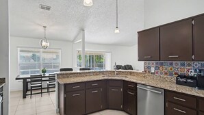 A modern kitchen with dark cabinets, a granite countertop, and a coffee bar. - Cozy Carribean/Mediterranean Home in Kissimmee, FL (Kissimmee)