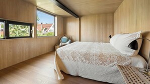 Un dormitorio con una cama grande, una ventana y vistas a casas.