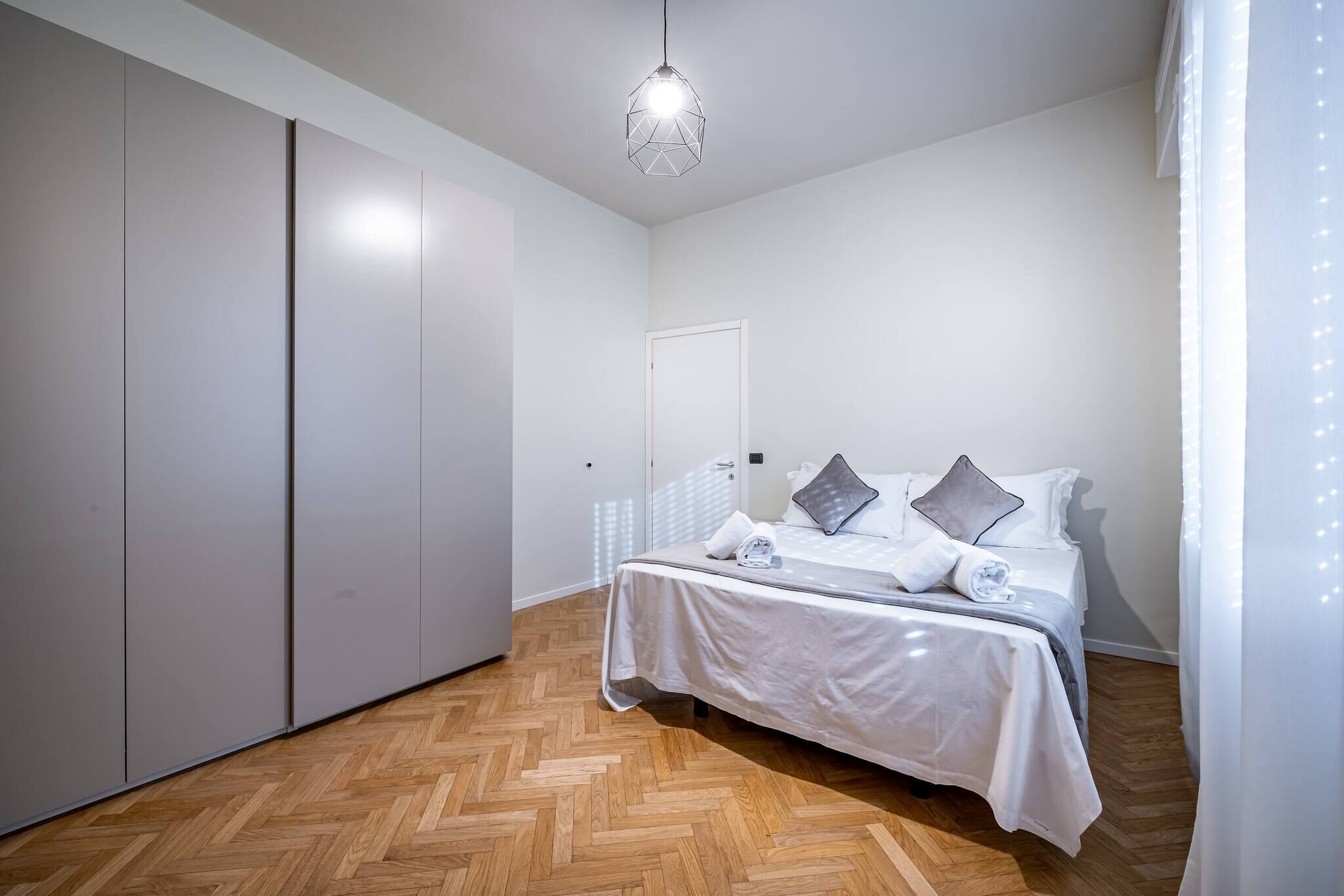 Une chambre à coucher avec un lit, une armoire et un luminaire suspendu.