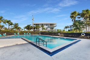 A rectangular swimming pool with a tiled edge, surrounded by a concrete deck. - Gulf-Front Condo | Panoramic Views | Marathon, FL (Marathon)