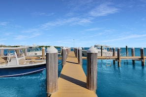 A wooden pier leading to a dock with boats, clear skies, and calm water. - Gulf-Front Condo | Panoramic Views | Marathon, FL (Marathon)