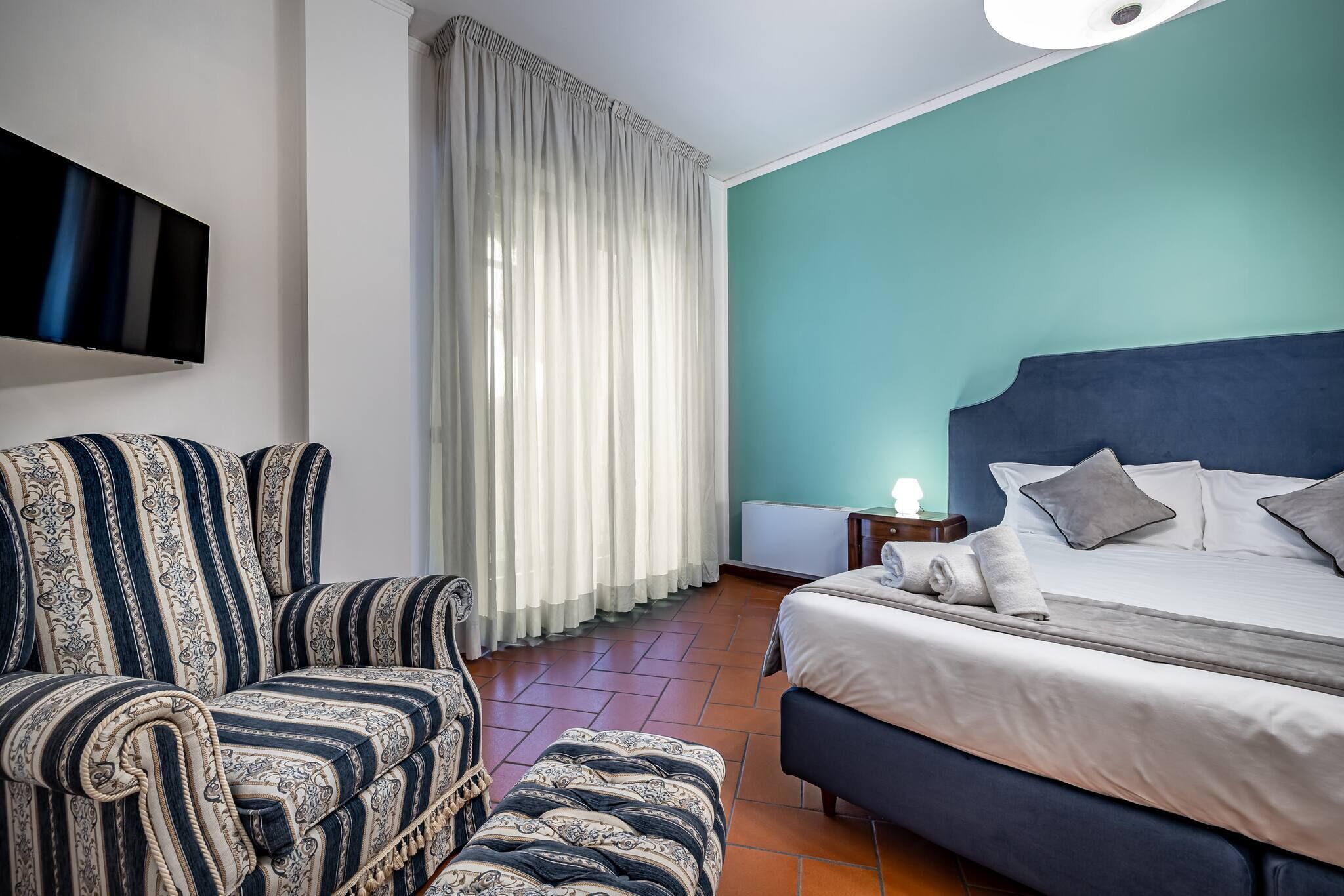 Une chambre d’hôtel avec un lit, un canapé, une télévision et des rideaux.