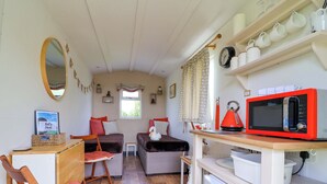A compact room with a bed, a small table, a chair, a microwave, and a refrigerator. - Sid's Nest (Whitchurch)