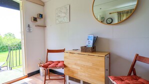 A room with a wooden desk, two chairs, a mirror, a map on the wall, and a door leading outside. - Sid's Nest (Whitchurch)