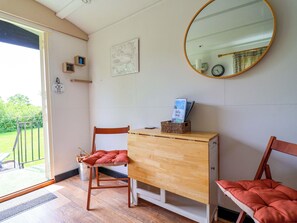 A room with a wooden desk, two chairs, a mirror, a map on the wall, and a door leading outside. - Sid's Nest (Whitchurch)
