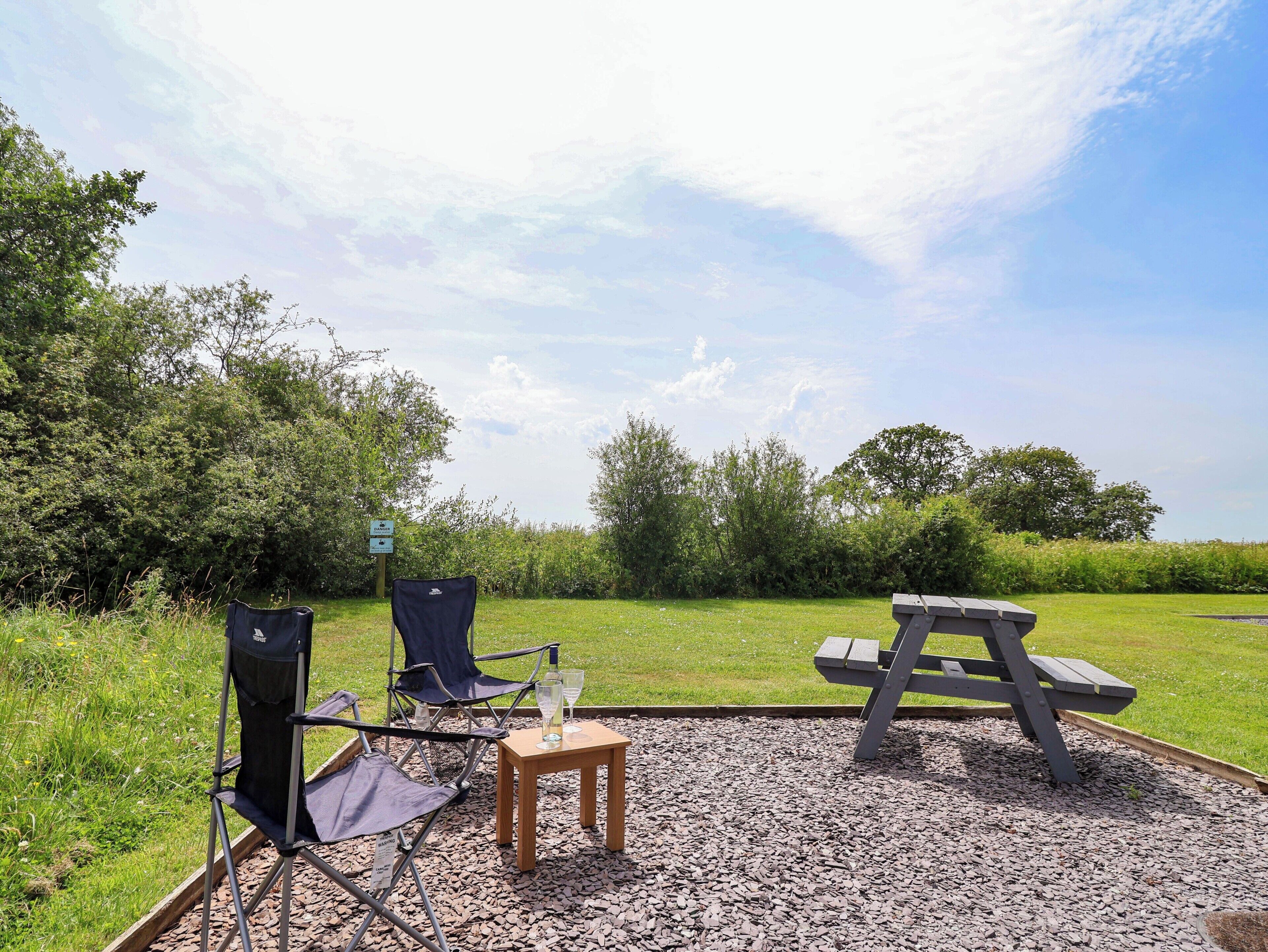 An outdoor seating area with a picnic table and two folding chairs.