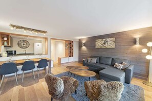 Ein modernes Wohnzimmer mit einem grauen Sofa, einem Holztisch und einem Essbereich mit Stühlen und Tisch.