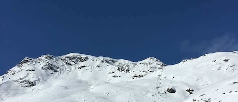 Une pente de montagne enneigée, avec des remontées mécaniques et des skieurs.