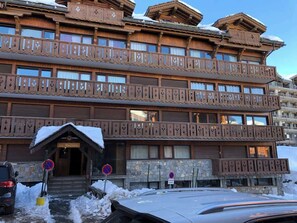 Ein mehrstöckiges Holzgebäude mit Balkonen und einem verschneiten Eingang.