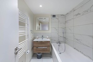Ein modernes Badezimmer mit einem weißen Waschbecken, einer Holzkommode und einer Badewanne.