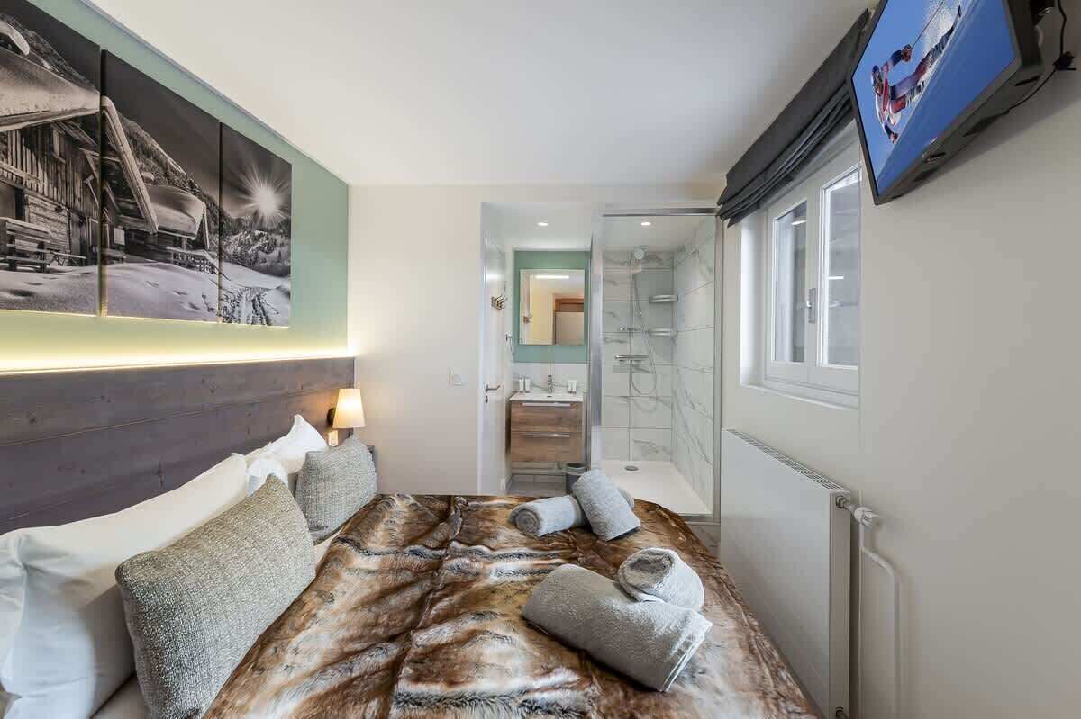 Une chambre d’hôtel avec un lit, un tableau, une télévision, une salle de bain et une douche.