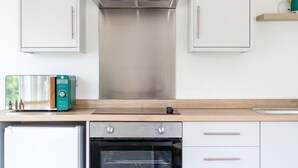 A kitchen with a built-in oven, a toaster, and a stainless steel range hood. - Newport Ship's Nook (Newport)