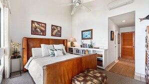 Ein Schlafzimmer mit einem Holzbett, einem Deckenventilator, einem Nachttisch mit Lampe und einem Bücherregal.