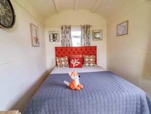 A bedroom with a red headboard, a plush fox toy on the bed, and a map on the wall. - Foxes Den (Whitchurch)