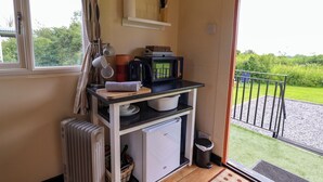 A compact kitchenette with a microwave, kettle, and small refrigerator. - Foxes Den (Whitchurch)