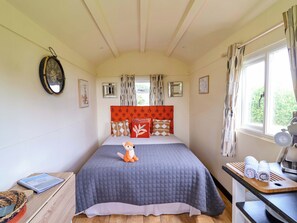 Ein Schlafzimmer mit Bett, Nachttisch, Fenster und Wanduhr.
