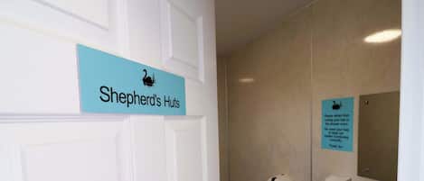 Une salle de bain avec une pancarte indiquant « Cabanes de berger » et un avis interdisant de se couper les cheveux sous la douche.