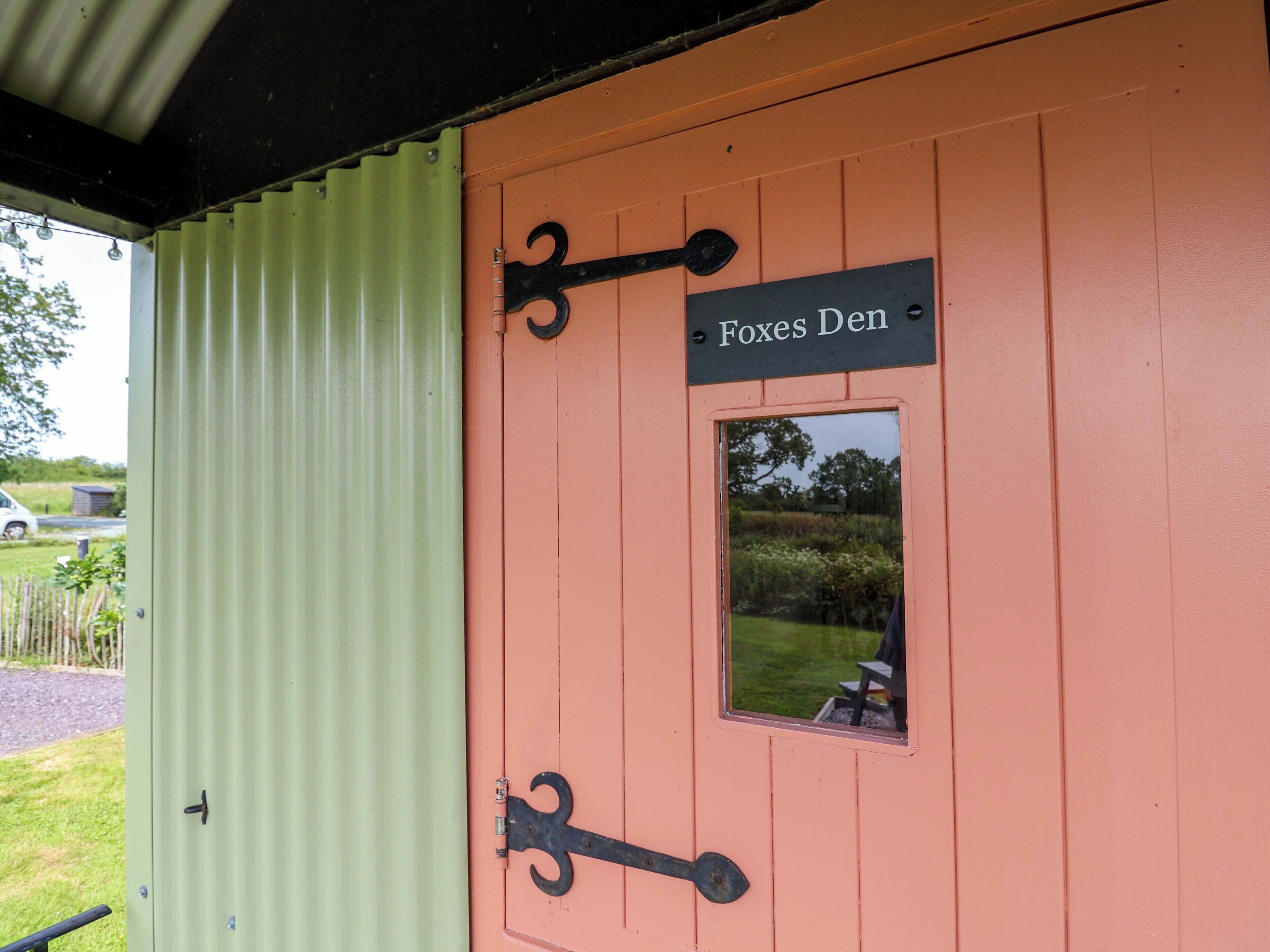 A door with a sign reading 'Foxes Den' and a small window.