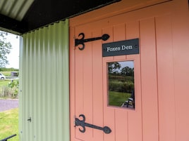 A door with a sign reading 'Foxes Den' and a small window.