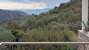 Varanda com vista para uma paisagem montanhosa e um corpo d'água.