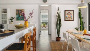 Uma cozinha moderna com área de jantar, uma planta grande em vaso e vista para o exterior.