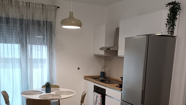 Een moderne keuken met een koelkast, een eettafel met stoelen en een bank.