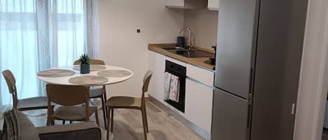 Una cocina moderna con refrigerador, una mesa de comedor con sillas y un sofá.