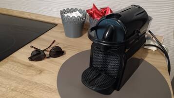 A coffee machine, a pair of sunglasses, and a tissue box on a wooden table.