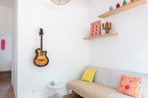 A room with a guitar hanging on the wall, a round white side table with a green candle, and a sofa with patterned cushions. - House with shared pool in Moliets (Moliets-et-Maa)