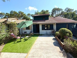 A house with a tiled roof, a covered patio with chairs, and a lawn. - House with shared pool in Moliets (Moliets-et-Maa)