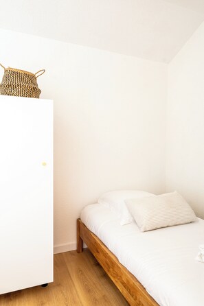 A bedroom with a wooden bed, white bedding, and a woven basket on a white wardrobe. - House with shared pool in Moliets (Moliets-et-Maa)