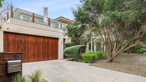 Une maison moderne avec un garage, une clôture en bois et un jardin bien entretenu.