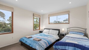 Quarto com duas camas, uma janela e uma mesa de cabeceira com abajur.