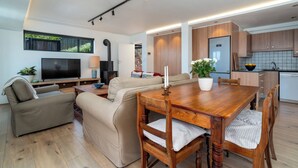 Una sala de estar moderna con televisor, sofá, mesa de comedor y zona de cocina.