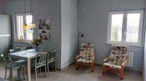 A dining area with a table, chairs, a vase with flowers, and wall art. - Abruzzo Wine & Nature Escape: Cozy Apartment in Bolognano, Italy (Santa Maria del Monte, Pescara)