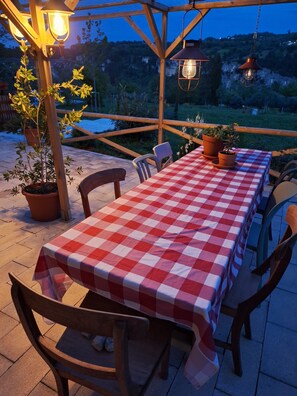 An outdoor patio with a checkered tablecloth, wooden chairs, potted plants, and hanging lanterns. - Abruzzo Wine & Nature Escape: Cozy Apartment in Bolognano, Italy (Santa Maria del Monte, Pescara)