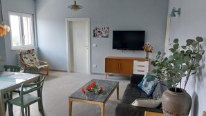Una sala de estar con sofá, mesa de centro, televisor, aparador y una silla.