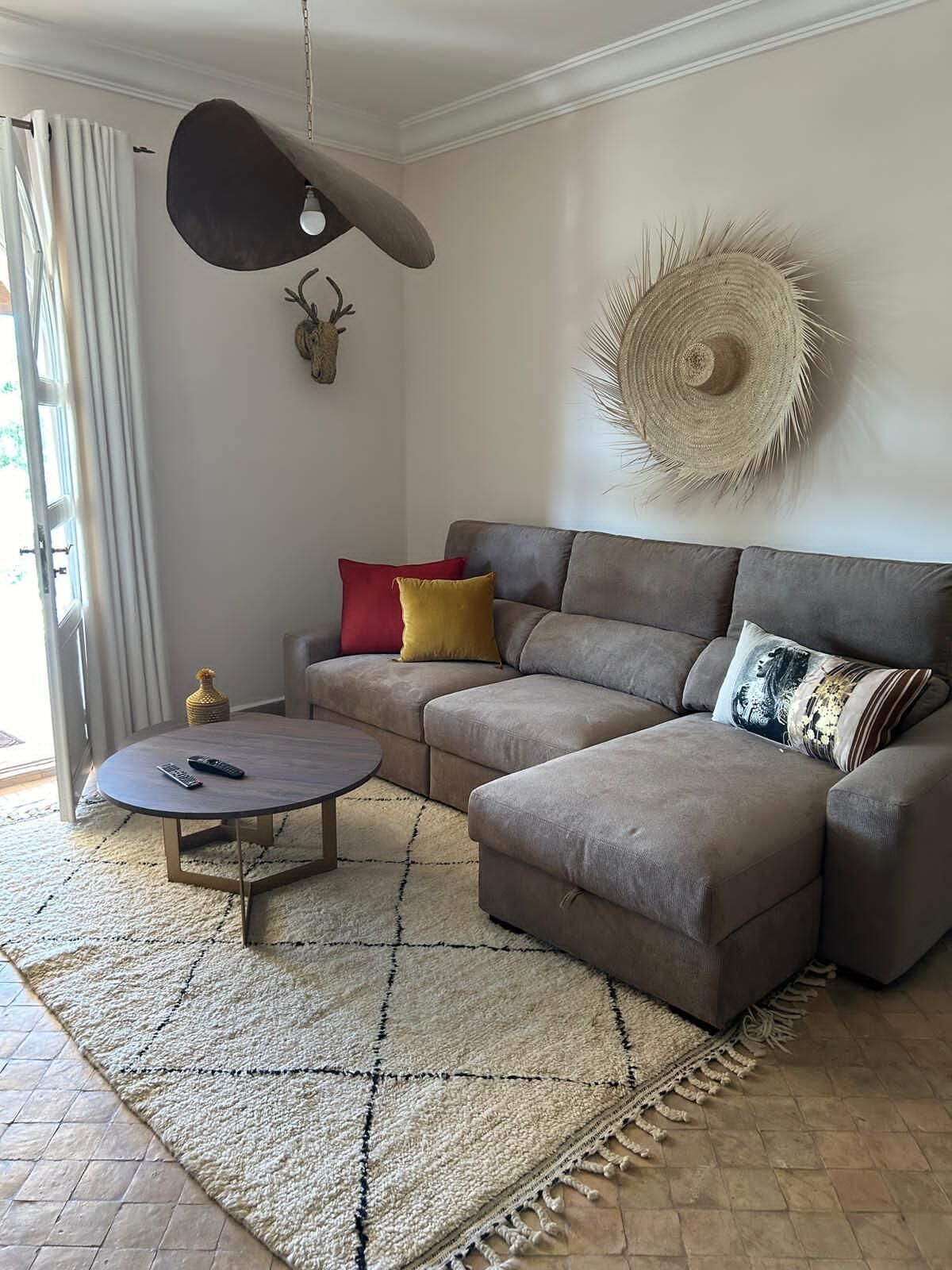 A living room with a sectional sofa, a round coffee table, a decorative wall hanging, and a rug.