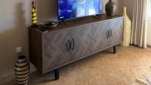 A living room with a TV, a cabinet, a vase, and a decorative bowl.