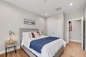 Ein Schlafzimmer mit Bett, Nachttisch, Lampe und einem gerahmten Bild an der Wand.