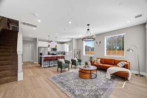 Ein zeitgemäßer Wohnbereich mit Treppe, Küchenzeile, Sofa und Esstisch.