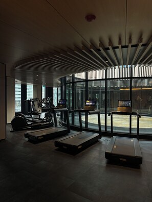 Een moderne sportschool met loopbanden, hometrainers en een digitale kiosk.