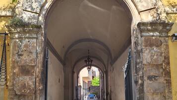 An arched stone corridor with a cobblestone floor leading to a gated entrance.