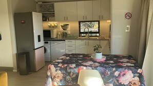 Cocina compacta con microondas, pileta y una planta en maceta sobre la encimera.